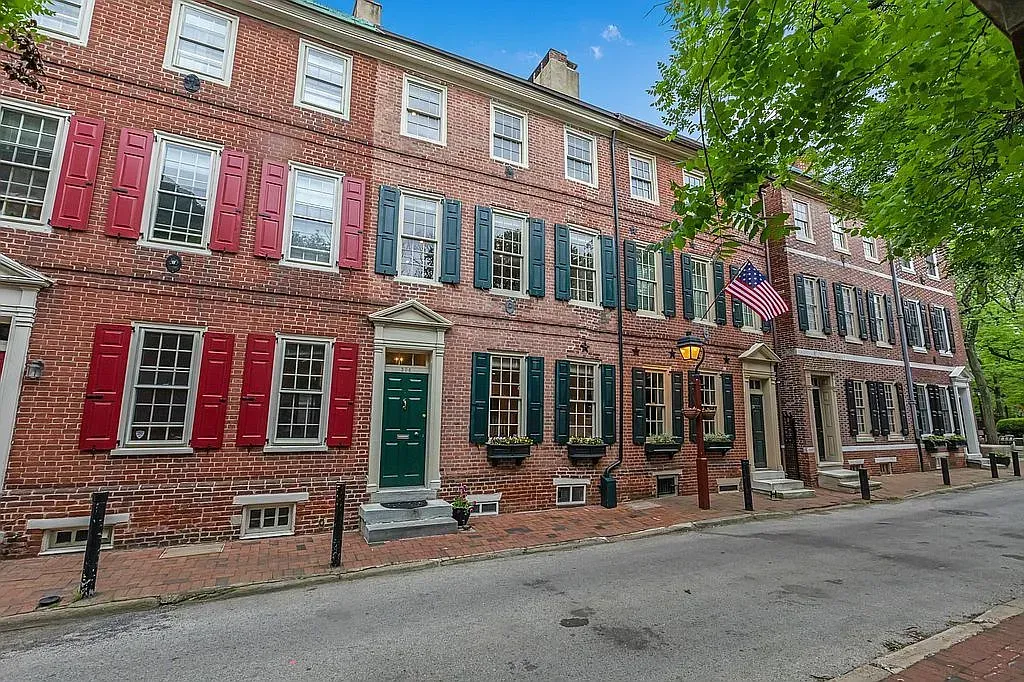 A row of brick houses with red shutters and green doors.