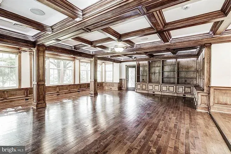 A large empty room with hardwood floors and a wooden ceiling.