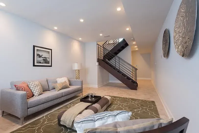 A living room with a couch and stairs leading up to the second floor.