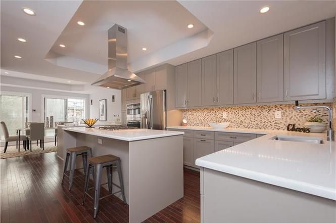 A kitchen with gray cabinets and white counter tops