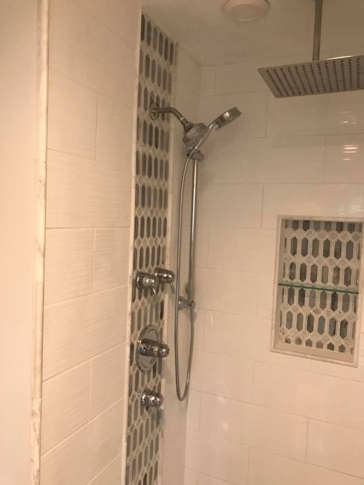A bathroom with a shower head and a ceiling fan.