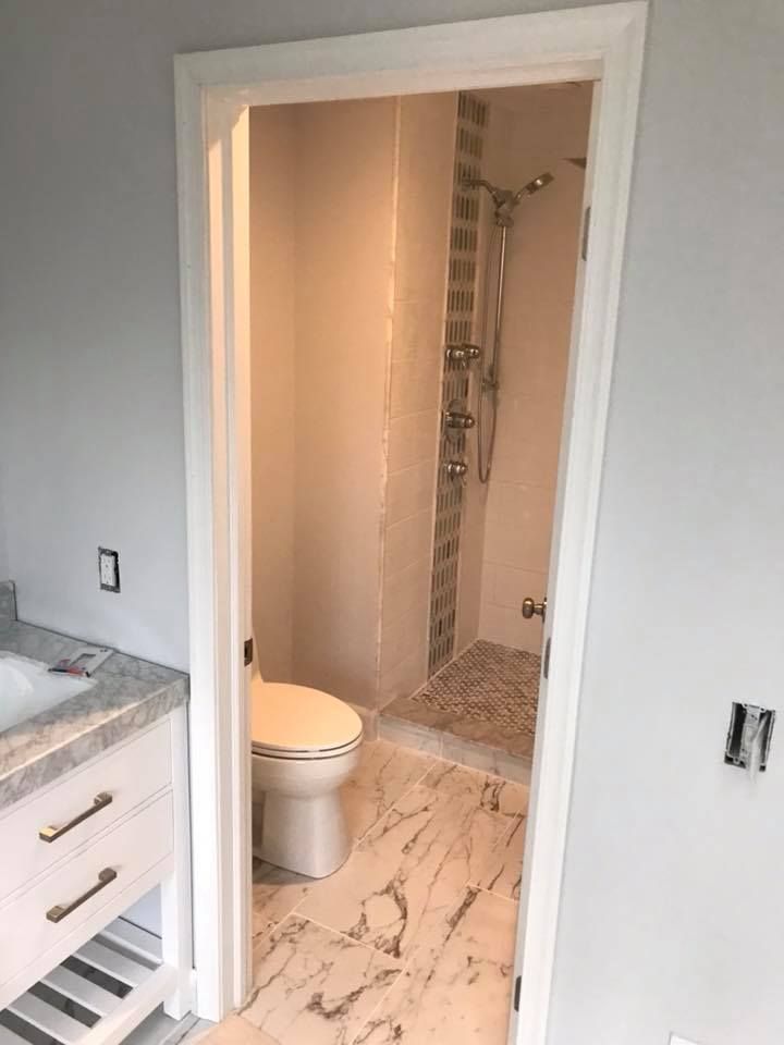 A bathroom with a toilet , sink and shower.
