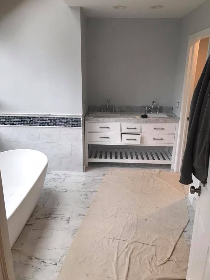 A bathroom with a tub , sink , and cabinets.