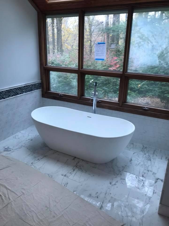 A bathtub is sitting in a bathroom next to a window.