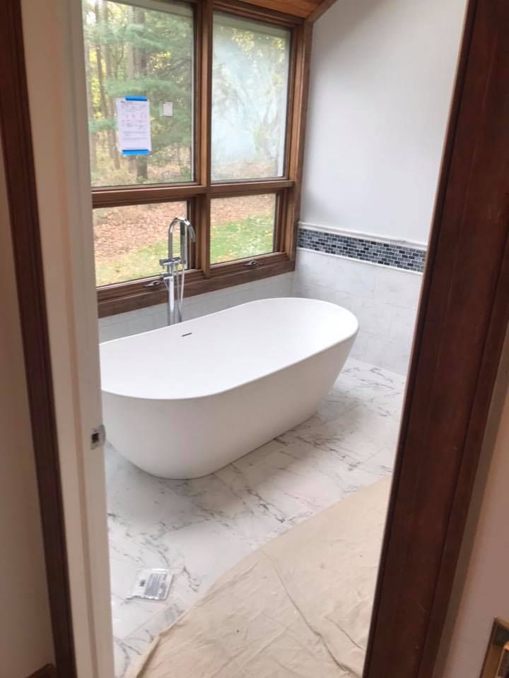 A bathroom with a bathtub and a window.