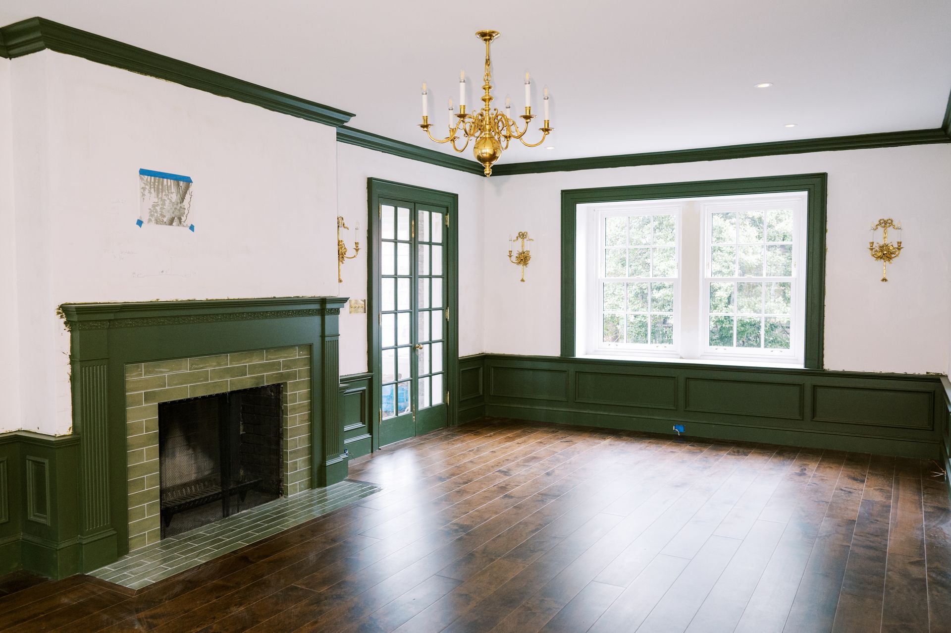 An empty living room with a fireplace and a chandelier.