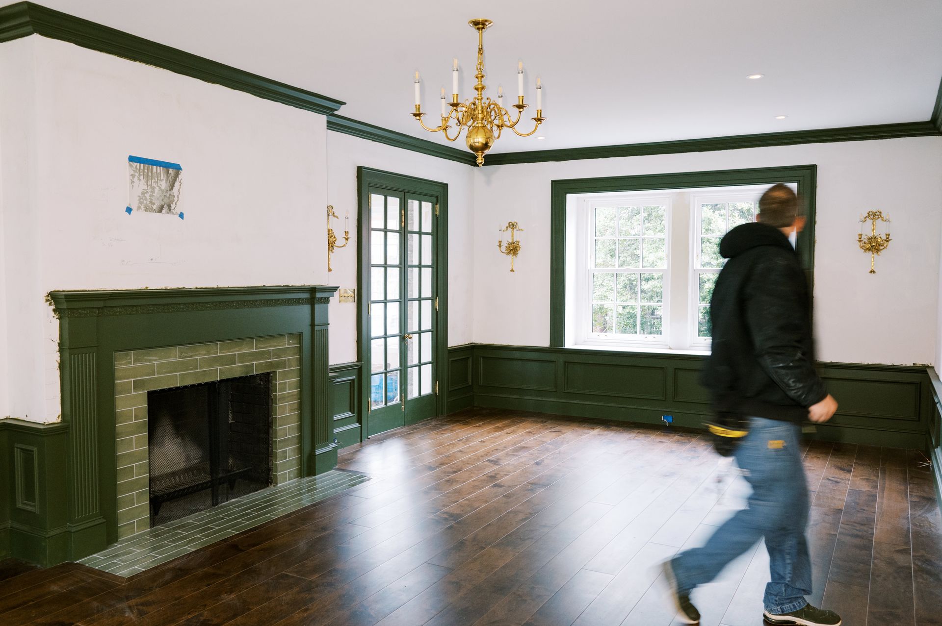 A man is walking through an empty living room with a fireplace.