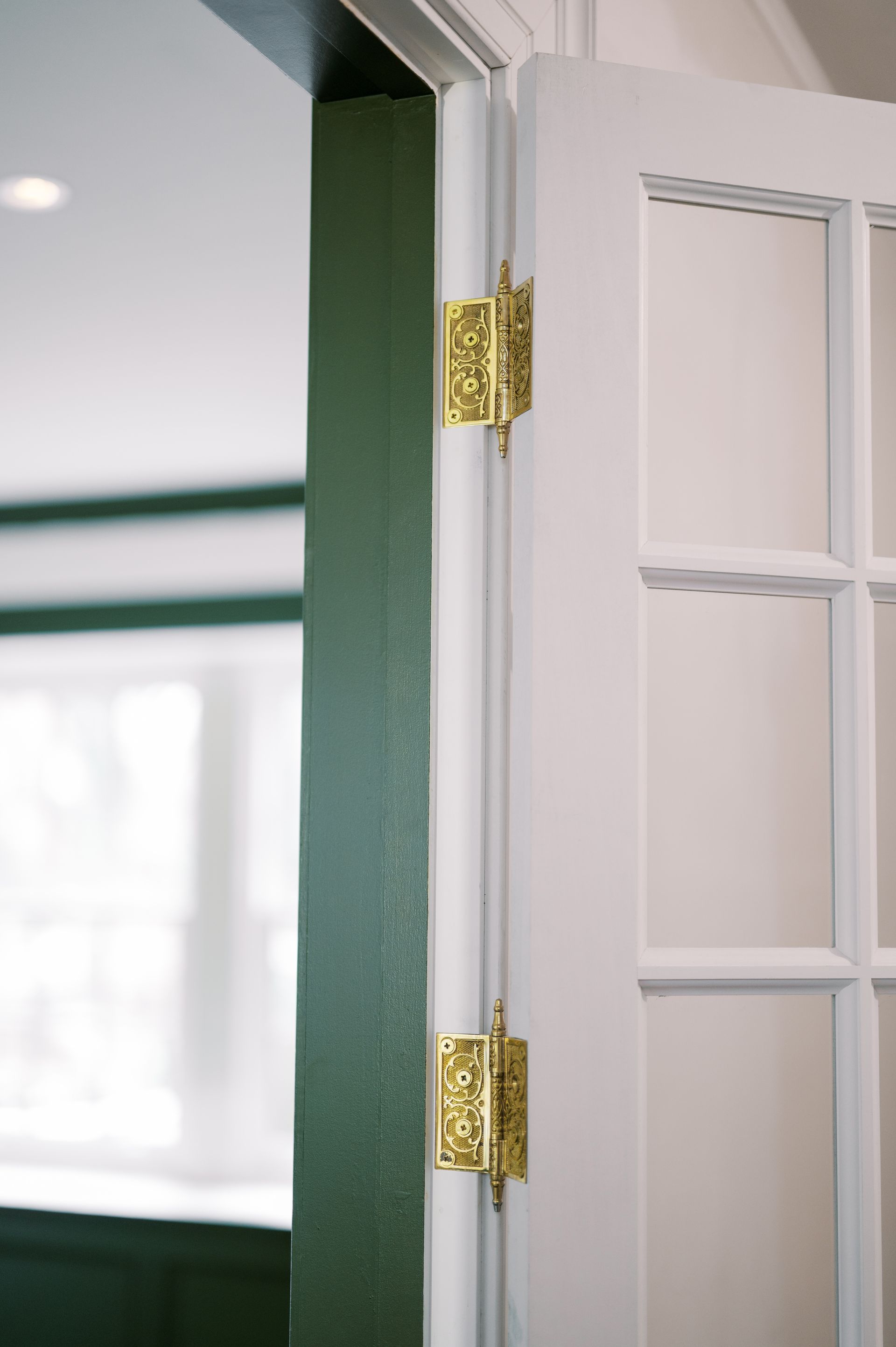 A close up of a white door with gold hinges in a room.