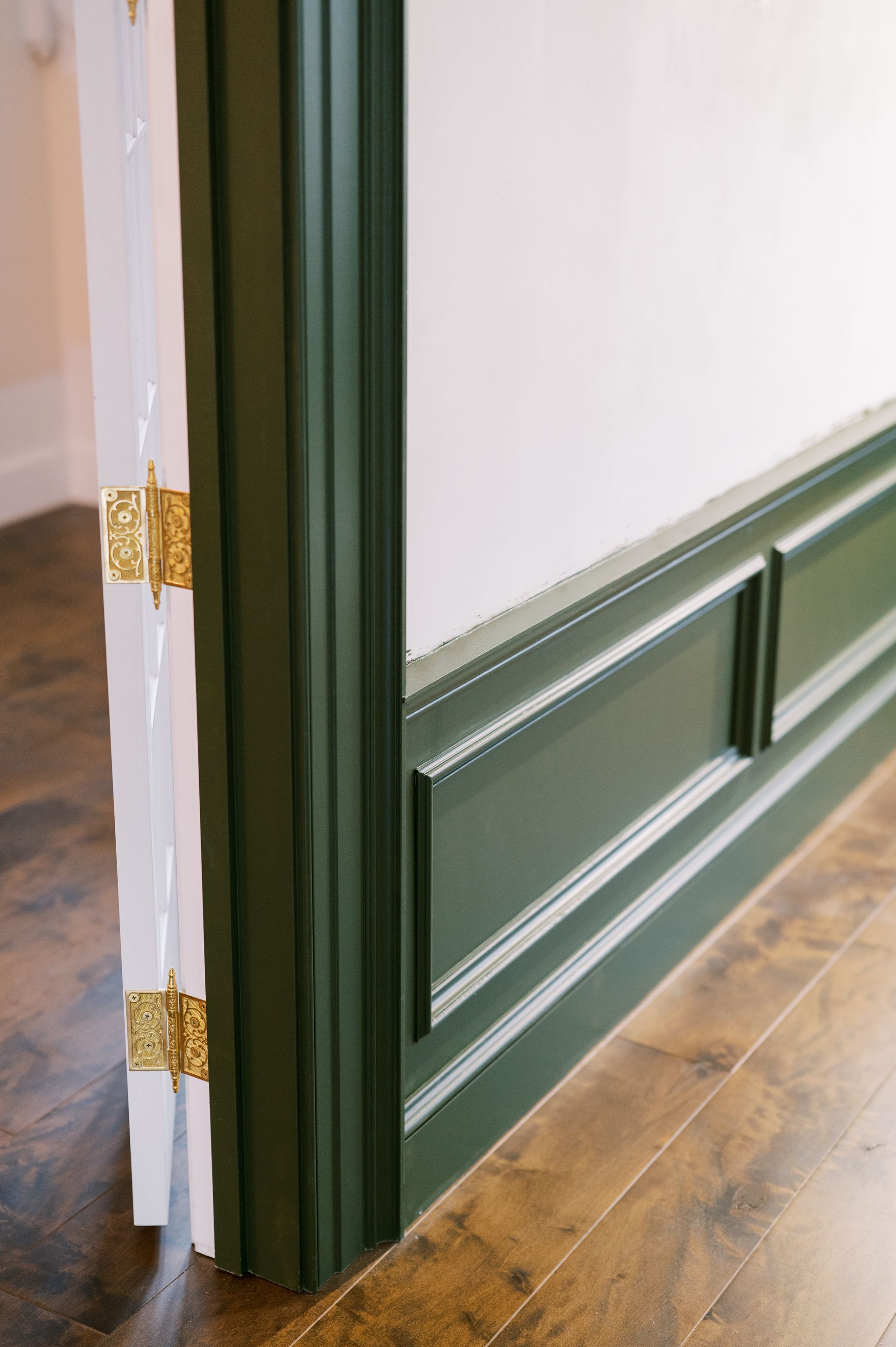 A door with a green trim and a wooden floor in a room.
