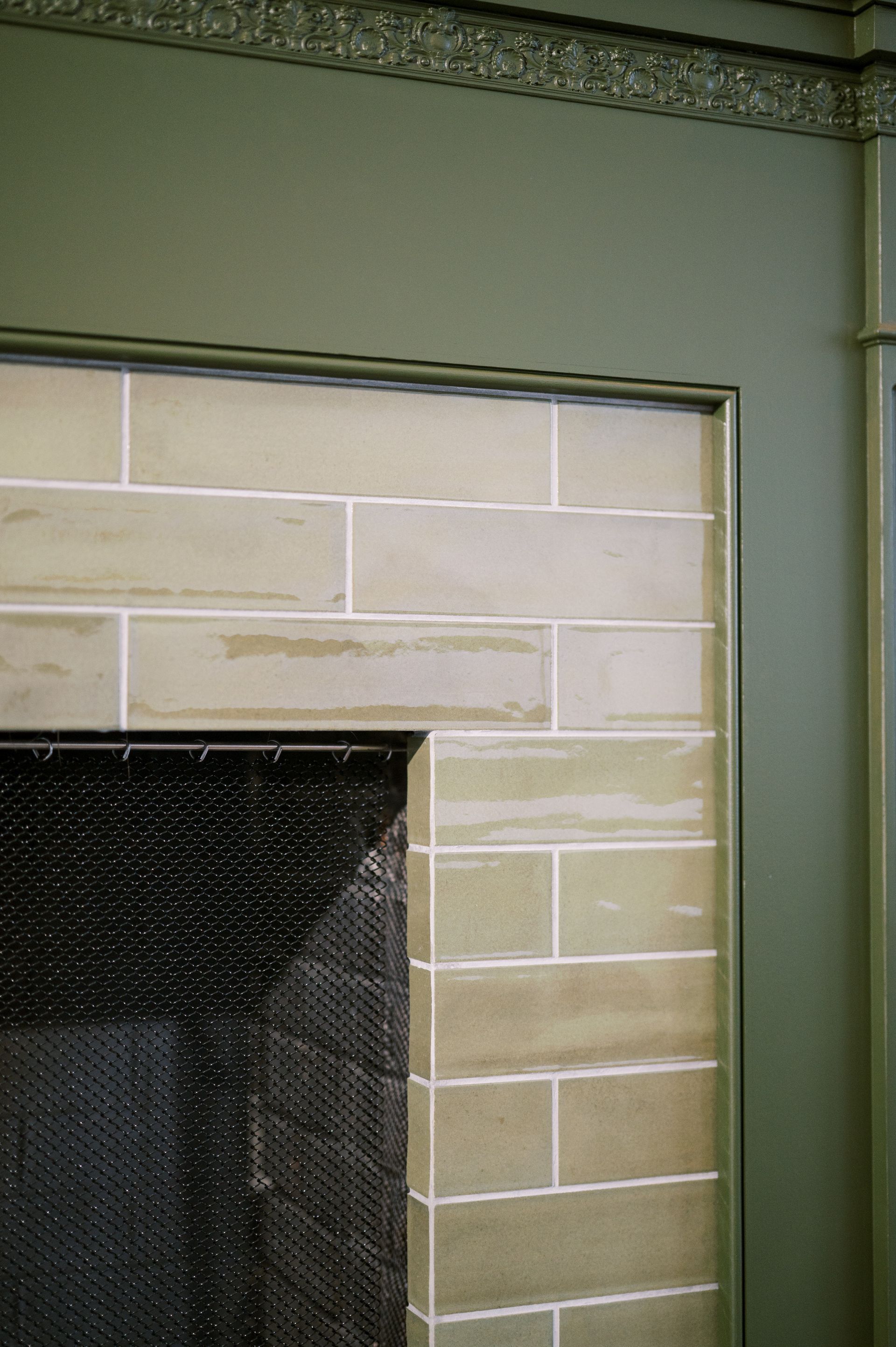 A close up of a fireplace with tiles on the wall.