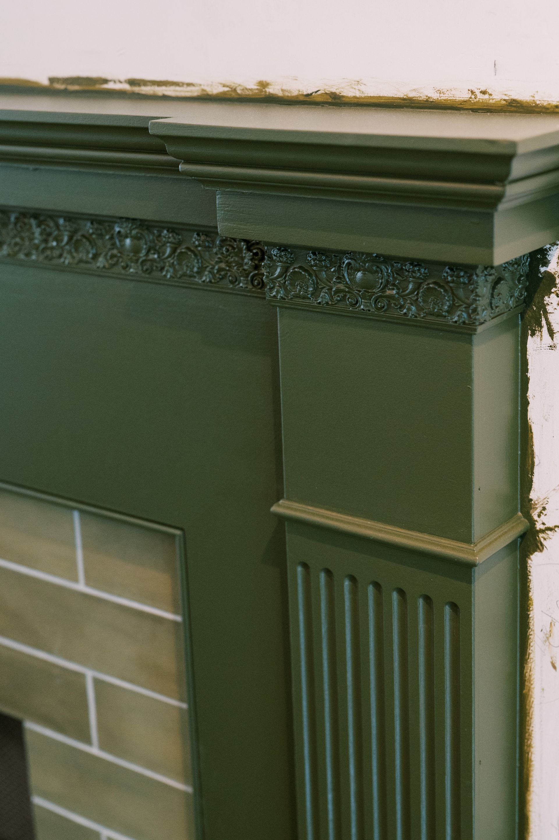 A green fireplace with a brick wall behind it