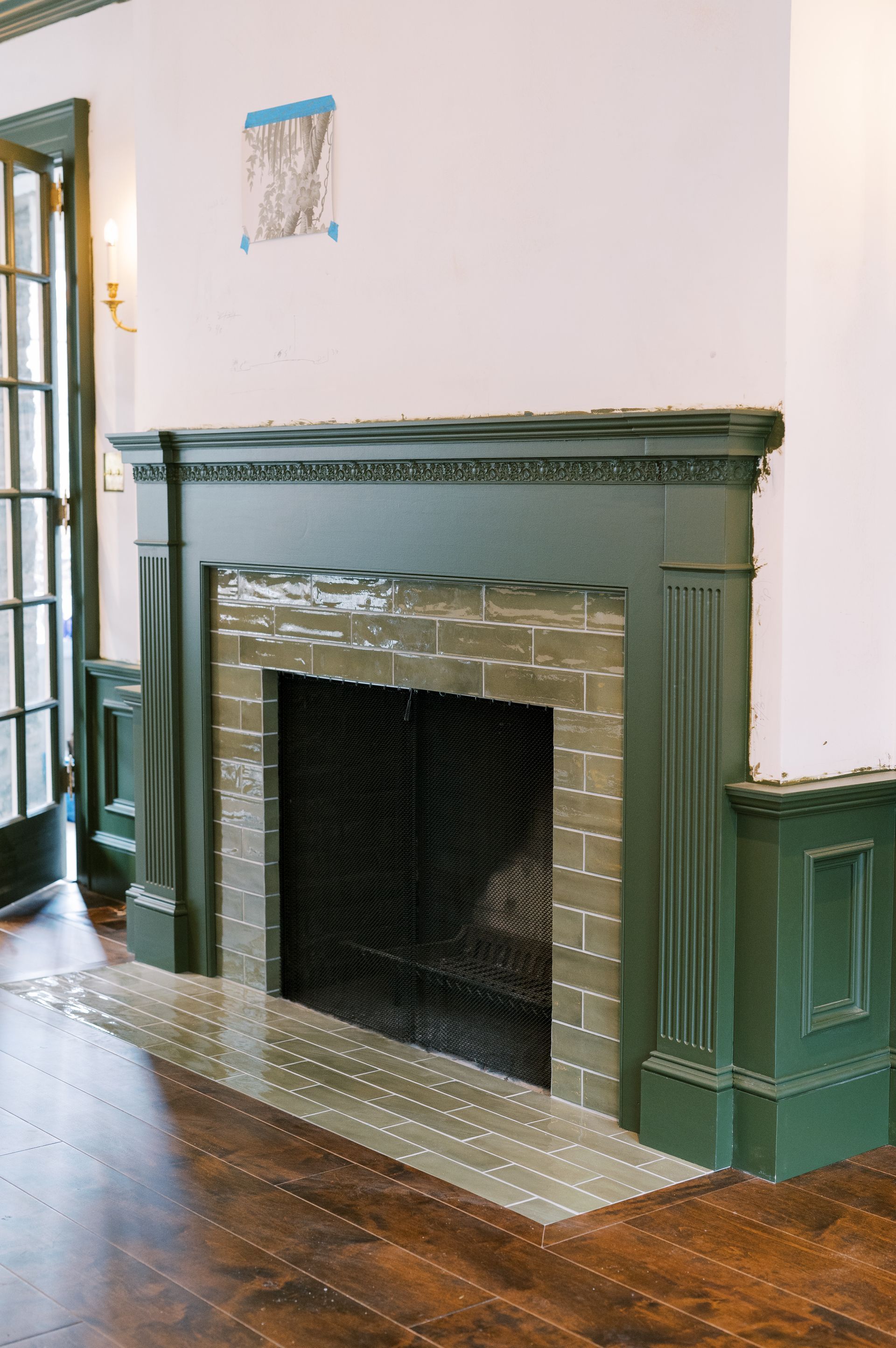 A fireplace with a green mantle in a living room.