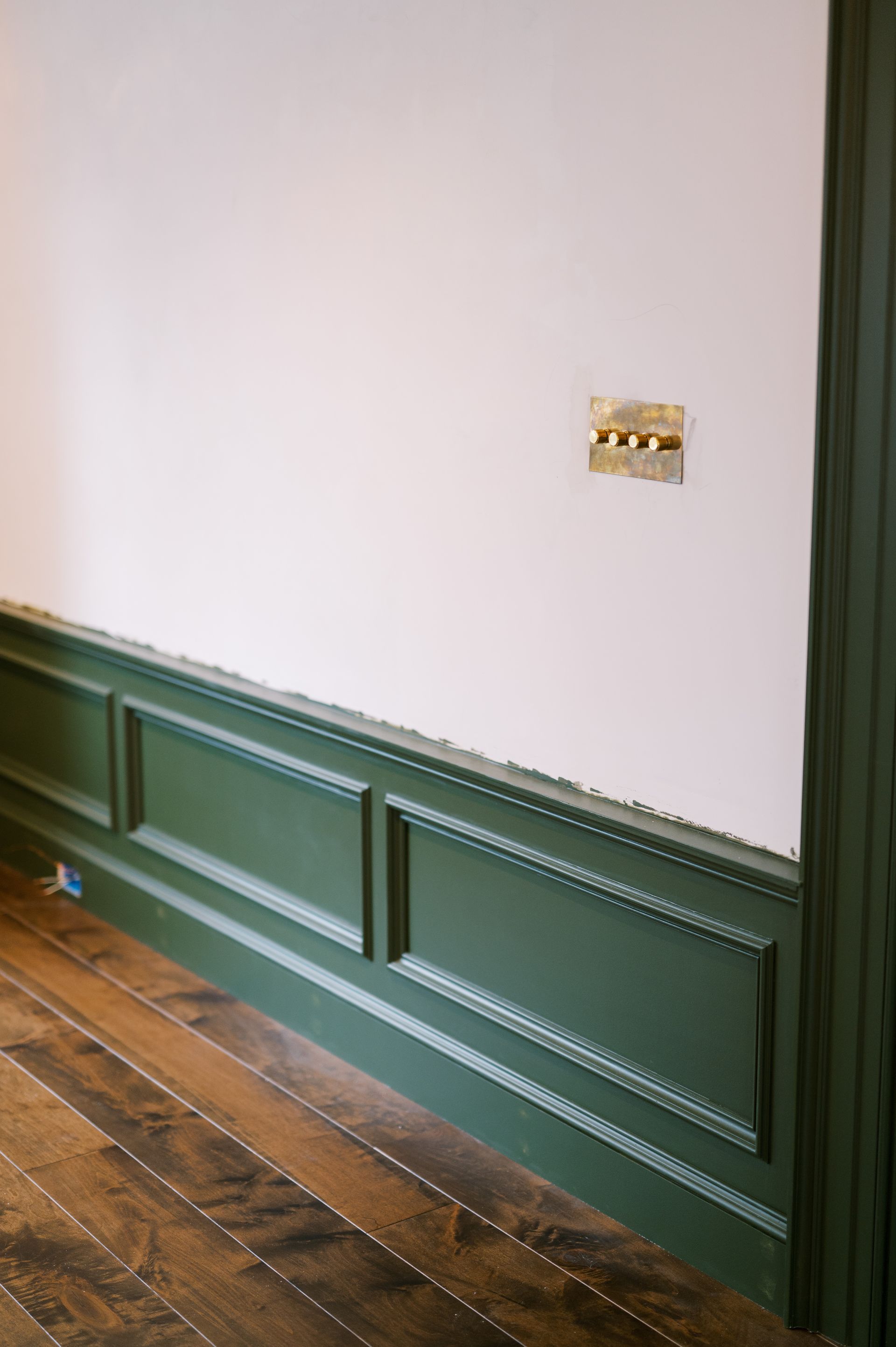 A room with green trim and a wooden floor.