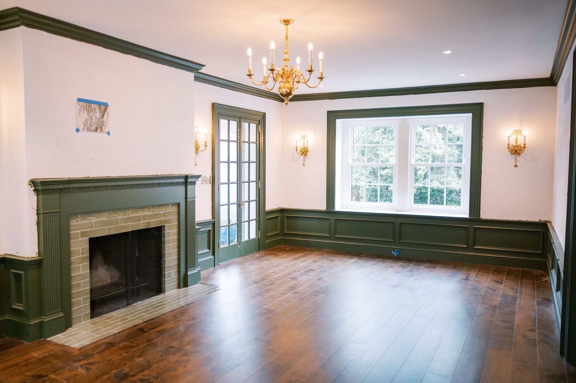 An empty living room with a fireplace and a chandelier.