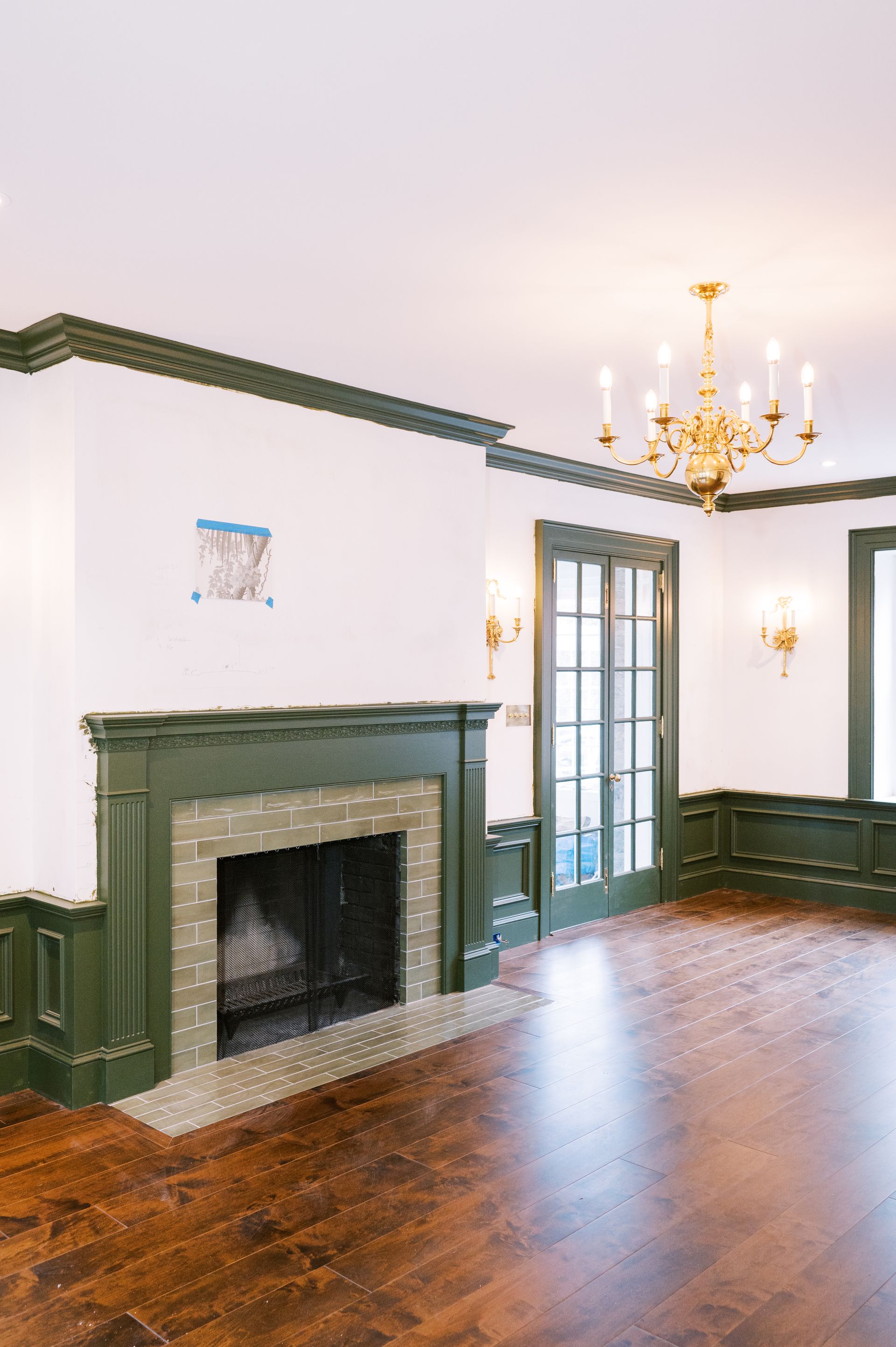 An empty living room with a fireplace and a chandelier.