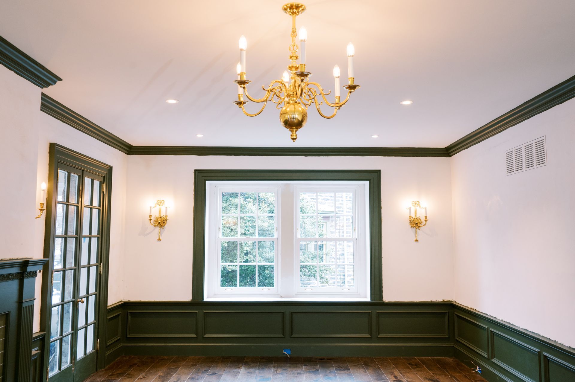 An empty room with a chandelier hanging from the ceiling and a window.