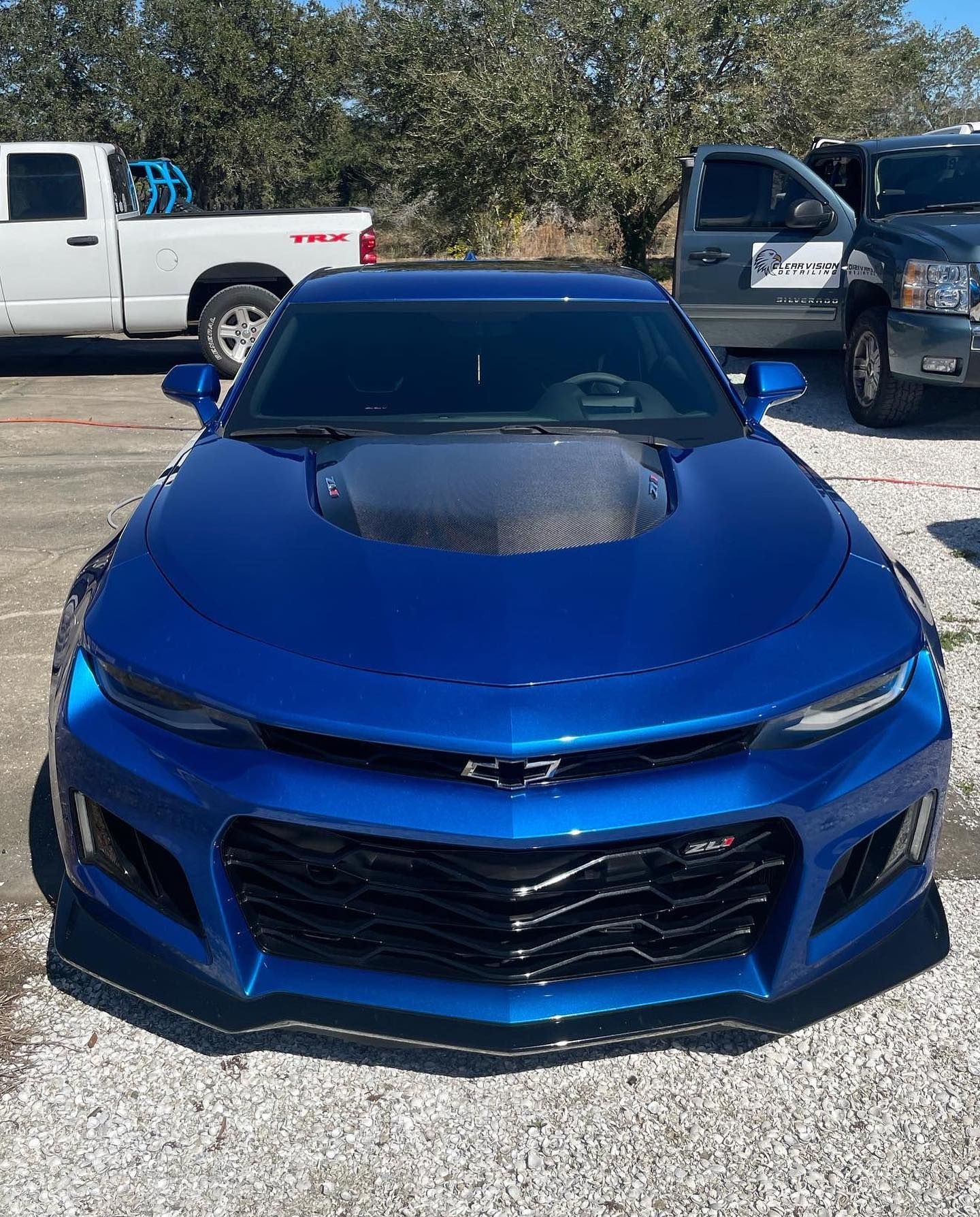 a blue car is parked in a parking lot next to a truck .