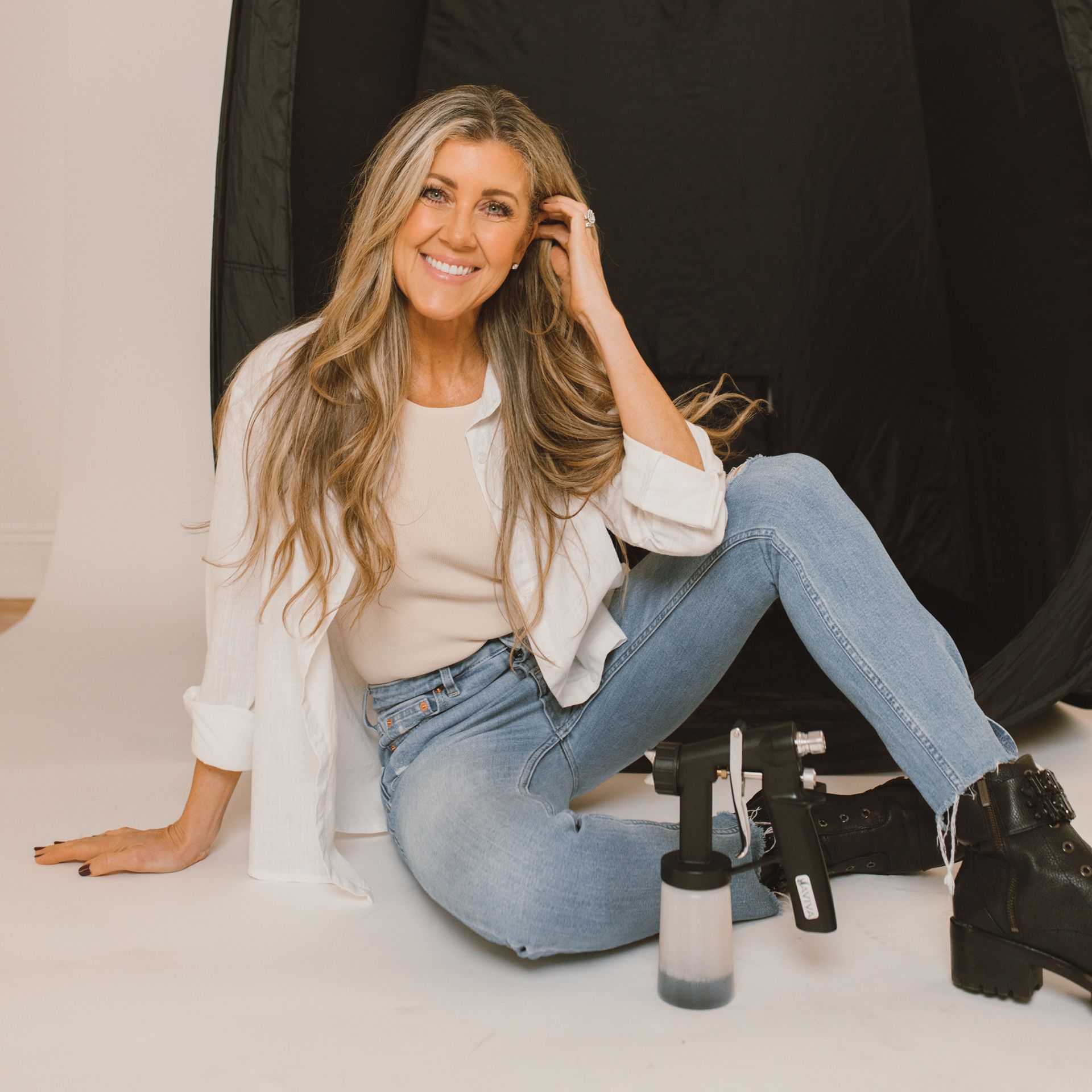 a woman is sitting on the floor next to a sprayer .