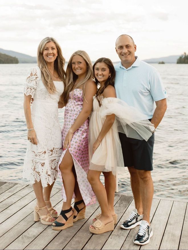 a family is posing for a picture on a dock next to a lake .