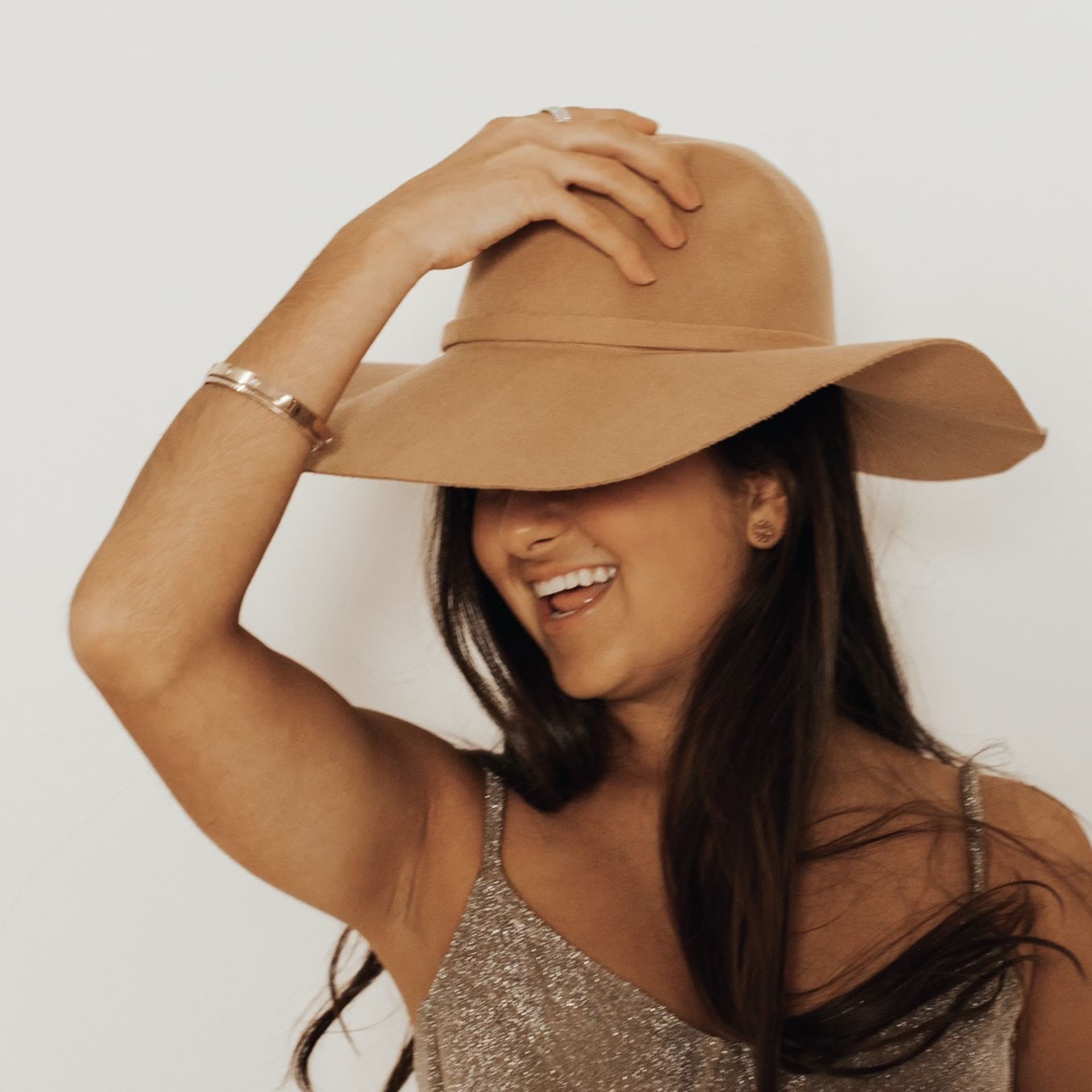 a woman wearing a hat covering her face with her hand