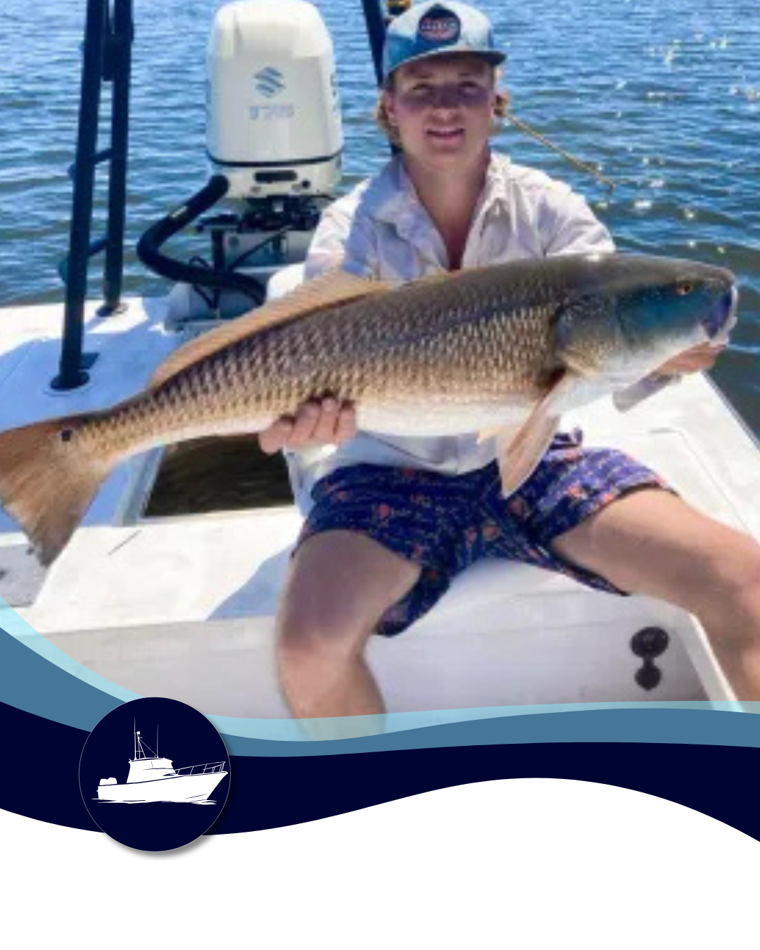 Young person holding a large redfish on a boat, smiling at the camera. Blue and white setting.