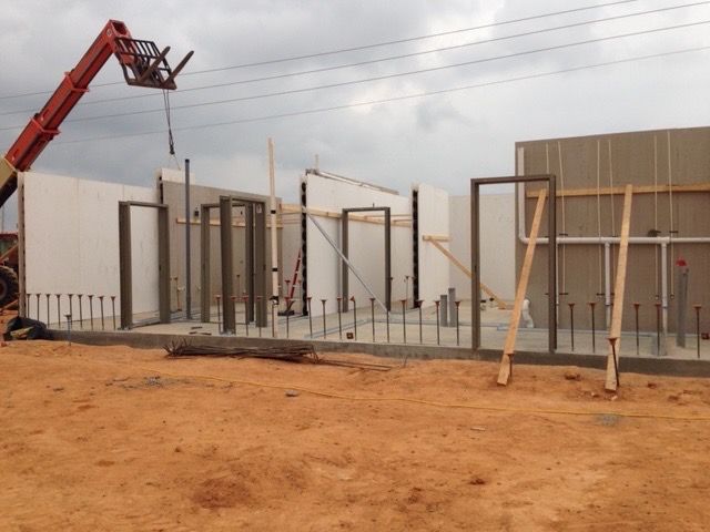A construction site with a crane lifting a wall