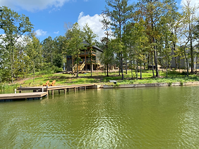 A house is sitting on the shore of a lake next to a dock.