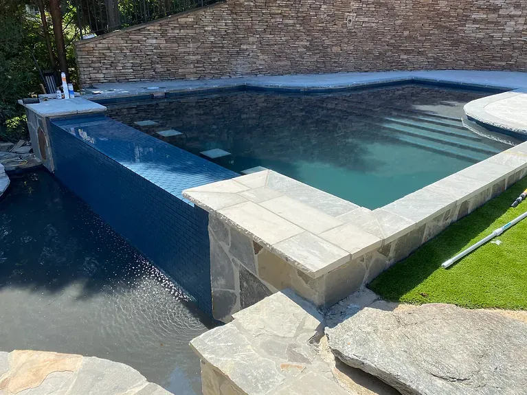 A large swimming pool with a stone wall surrounding it.