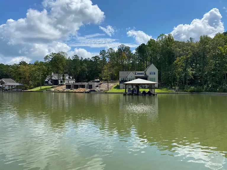 A large body of water with a dock and a house in the background.