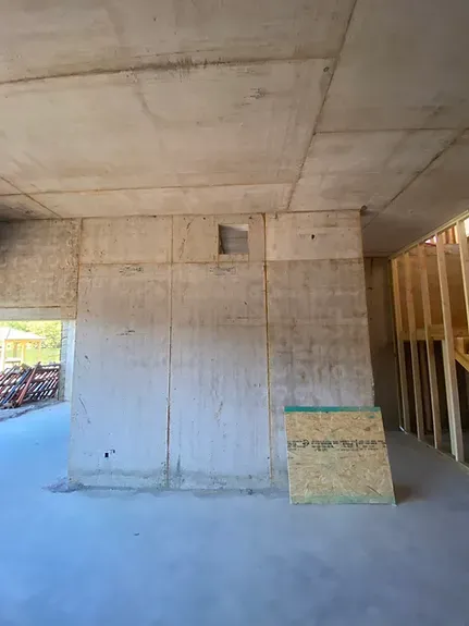 A room with a concrete wall and a ceiling in a building under construction.