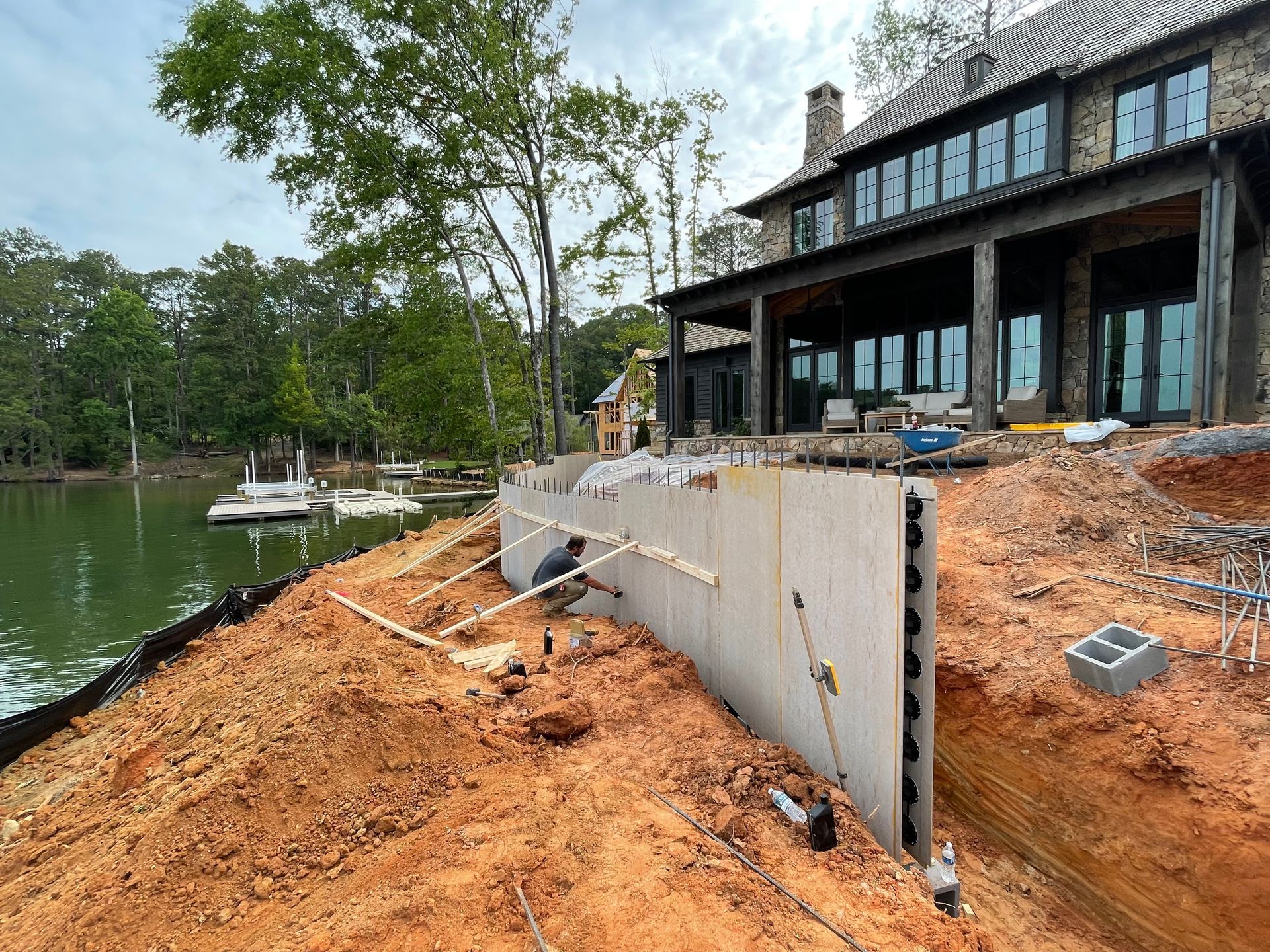 A large sea wall is being built on the shore of a lake house.