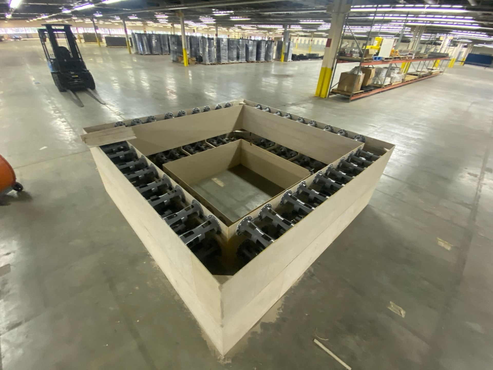 A large cardboard box in a warehouse with a forklift in the background.