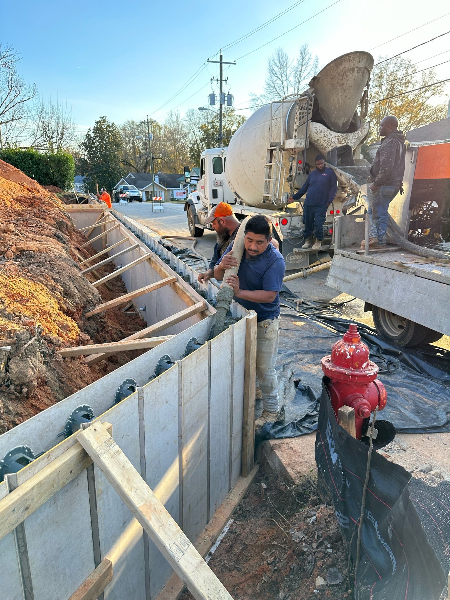 A group of construction workers are working on a concrete wall next to a fire hydrant.