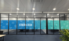 Office meeting room with glass windows, STREAM TECH logo, and blue/teal graphics.