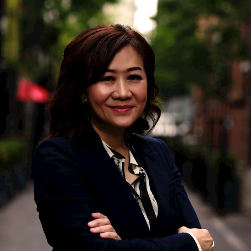 A woman in a suit is standing with her arms crossed