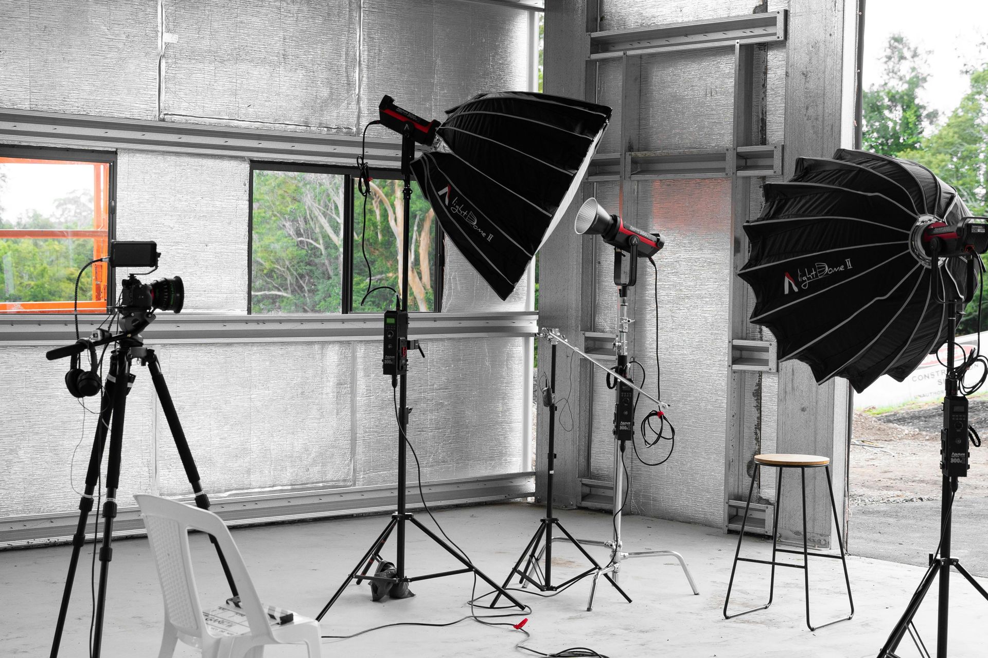 Photo studio setup with camera on tripod, lights, and a stool.