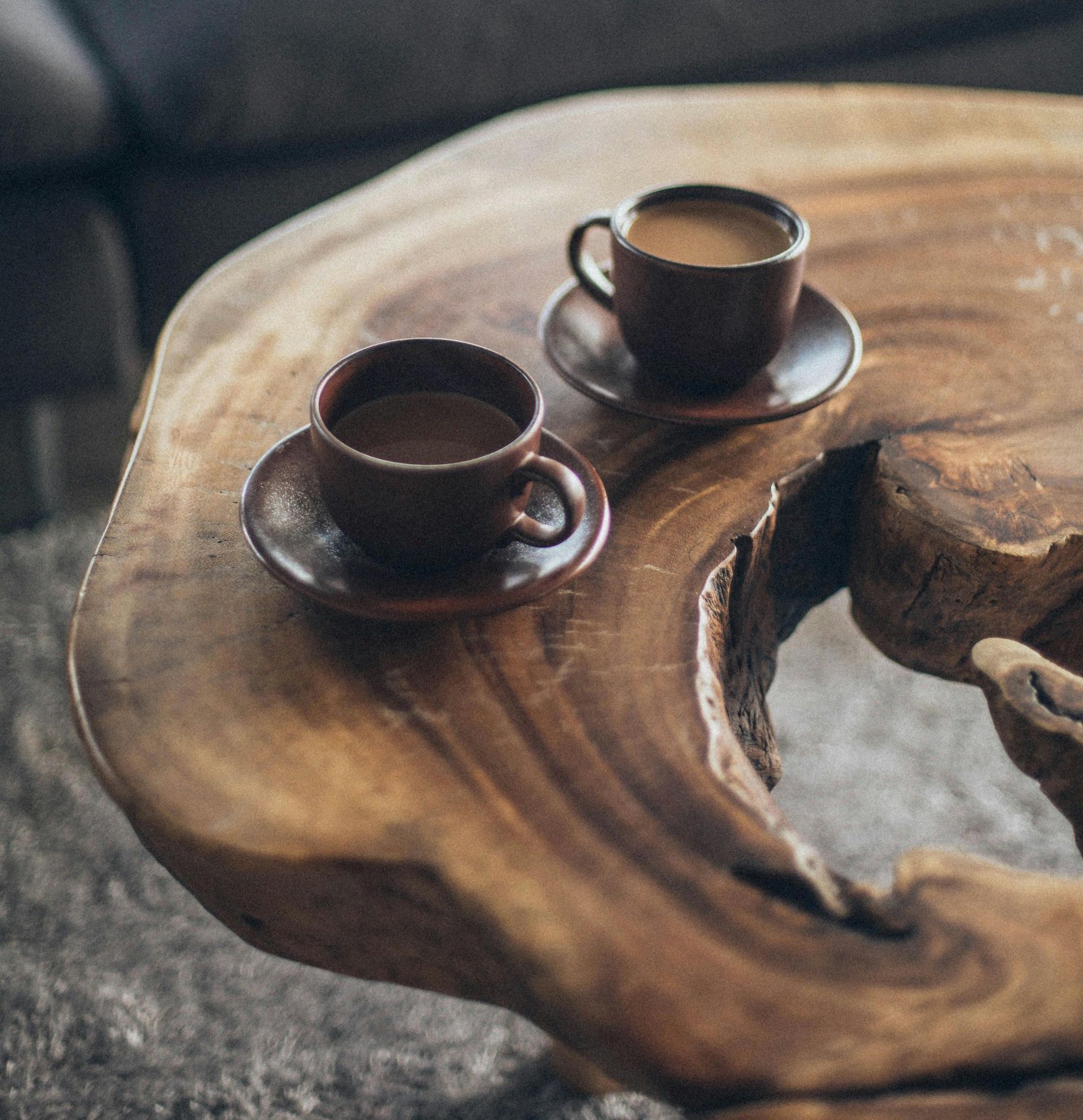 Two cups of coffee are sitting on a wooden table.