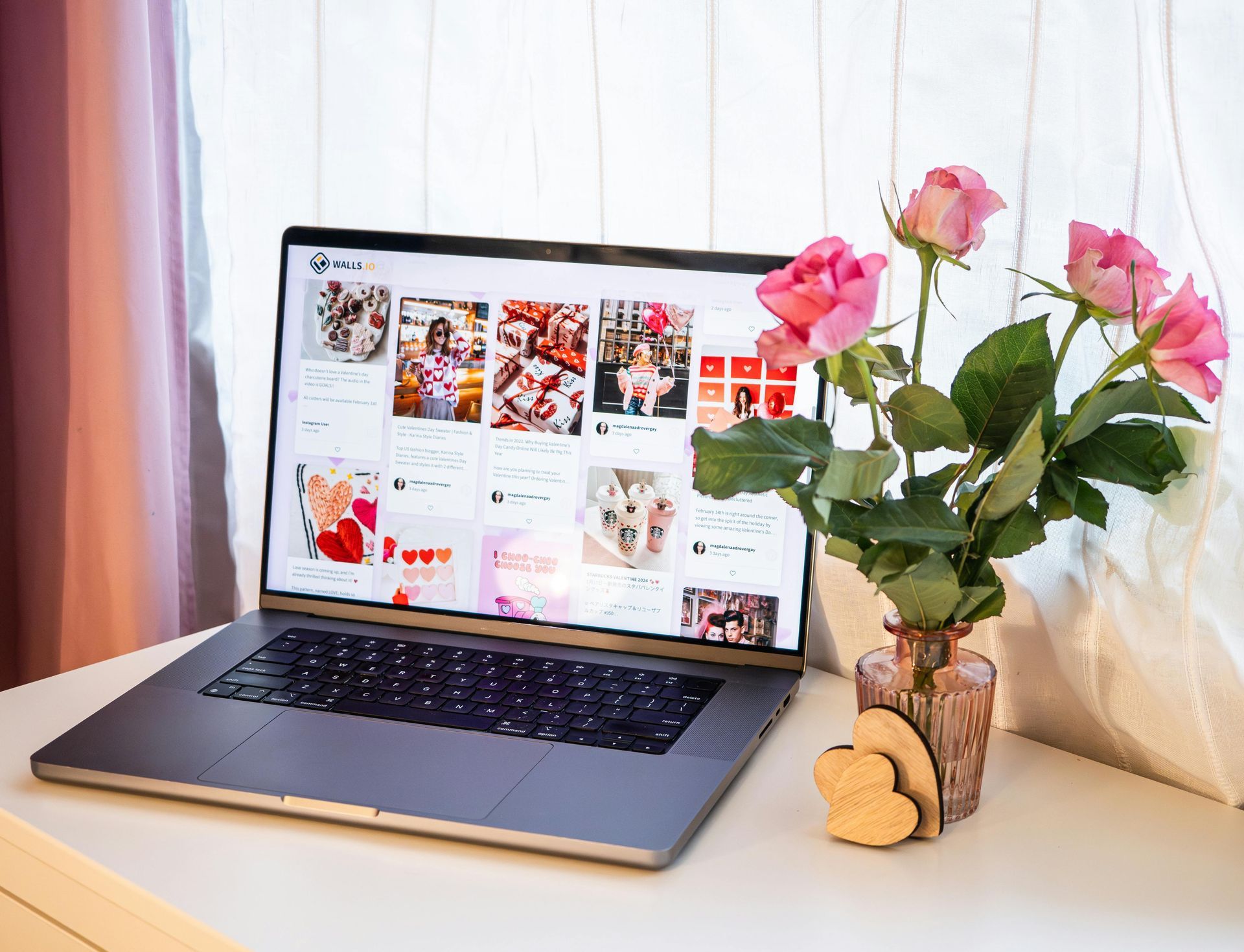 Laptop displaying Pinterest board with pink roses in a decorative vase on a white table.