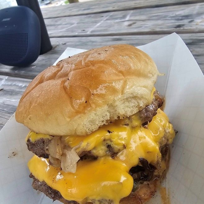 A close up of a hamburger with cheese on a bun.