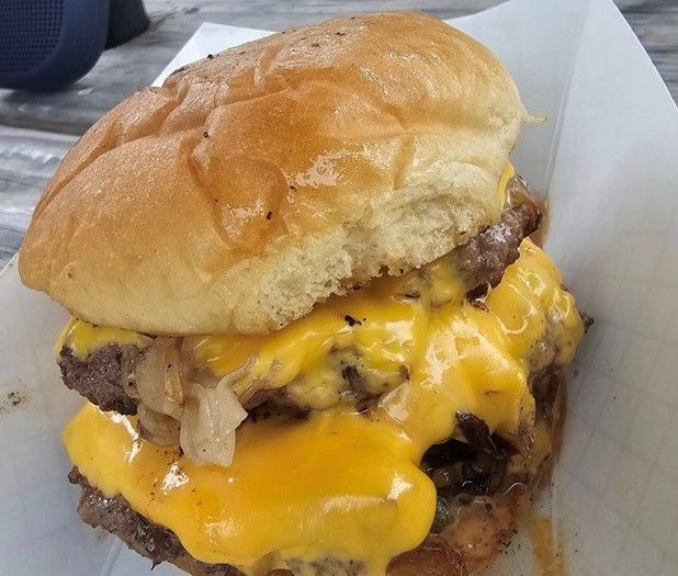 A close up a burger with cheese, onions on a bun.