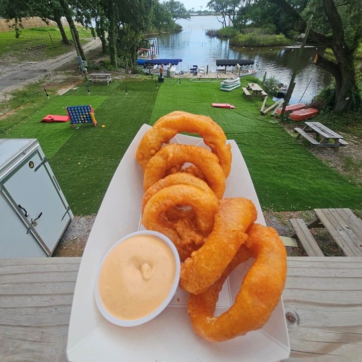 A plate of onion rings with a side of dipping sauce.