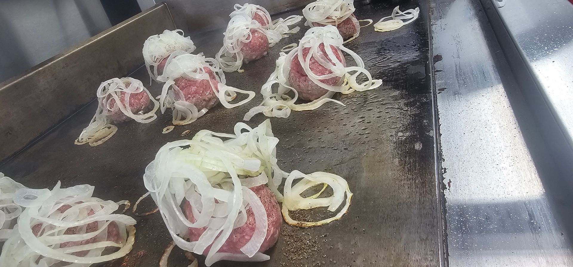 Smash burgers with onions on a grill.