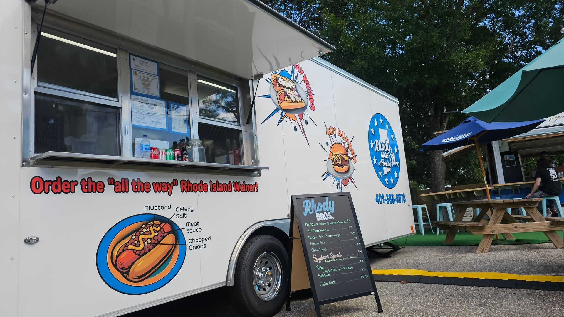 A white food truck is parked in a parking lot.