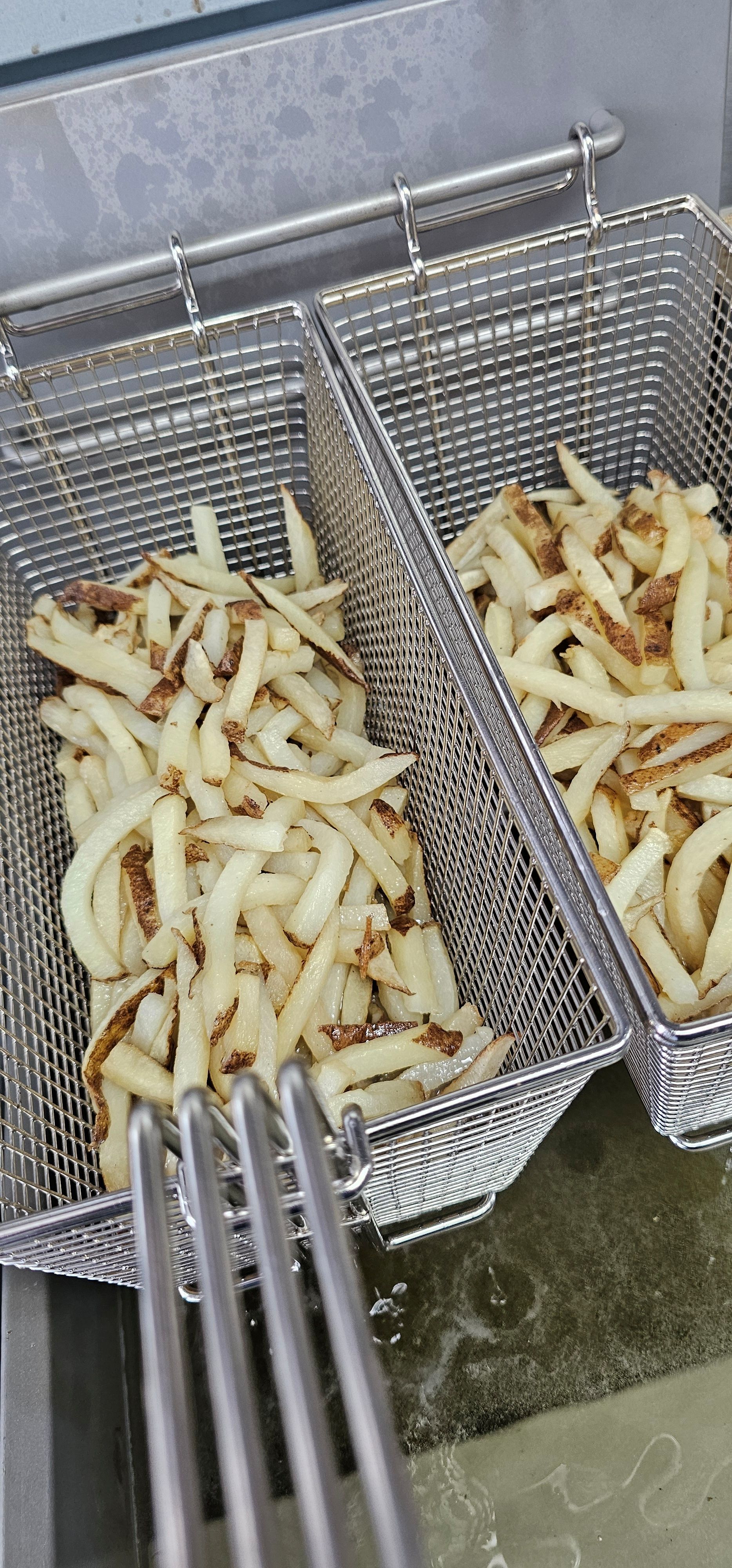 Fries deep frying in a basket.