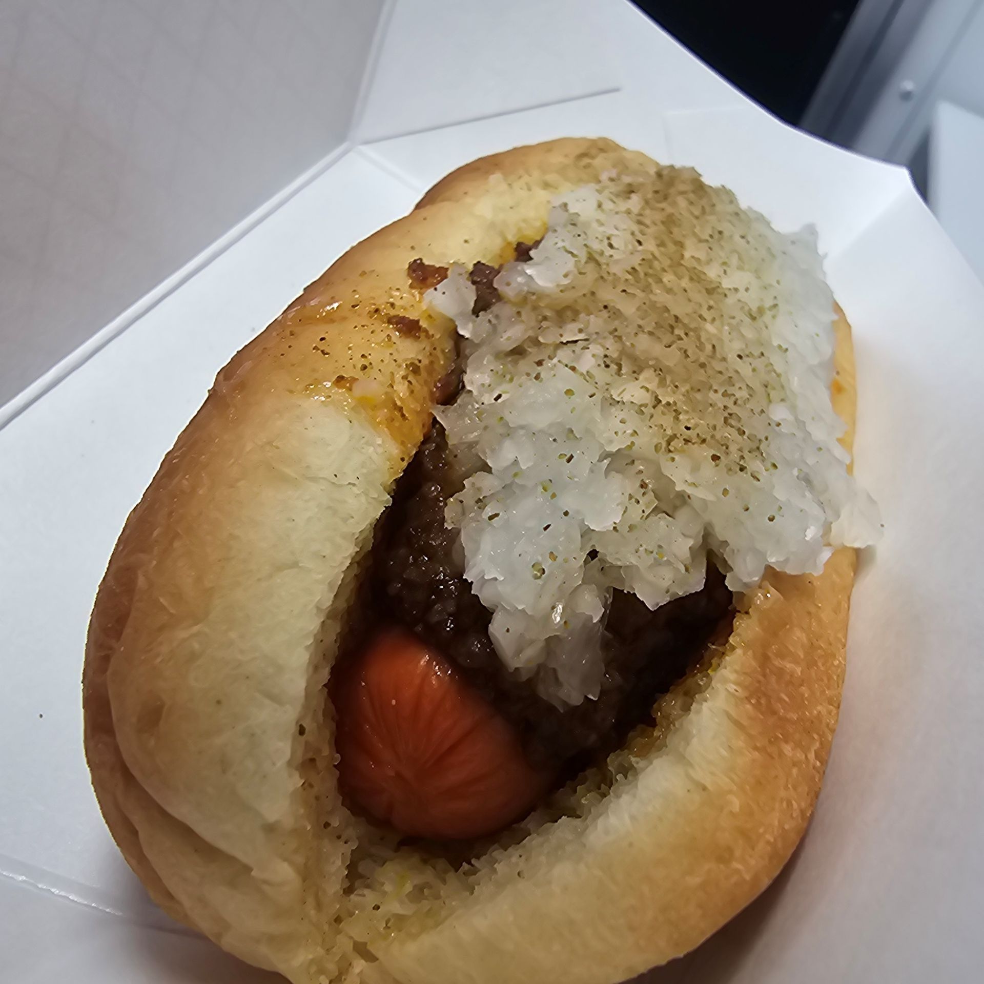 A wiener on a bun with onions on top.
