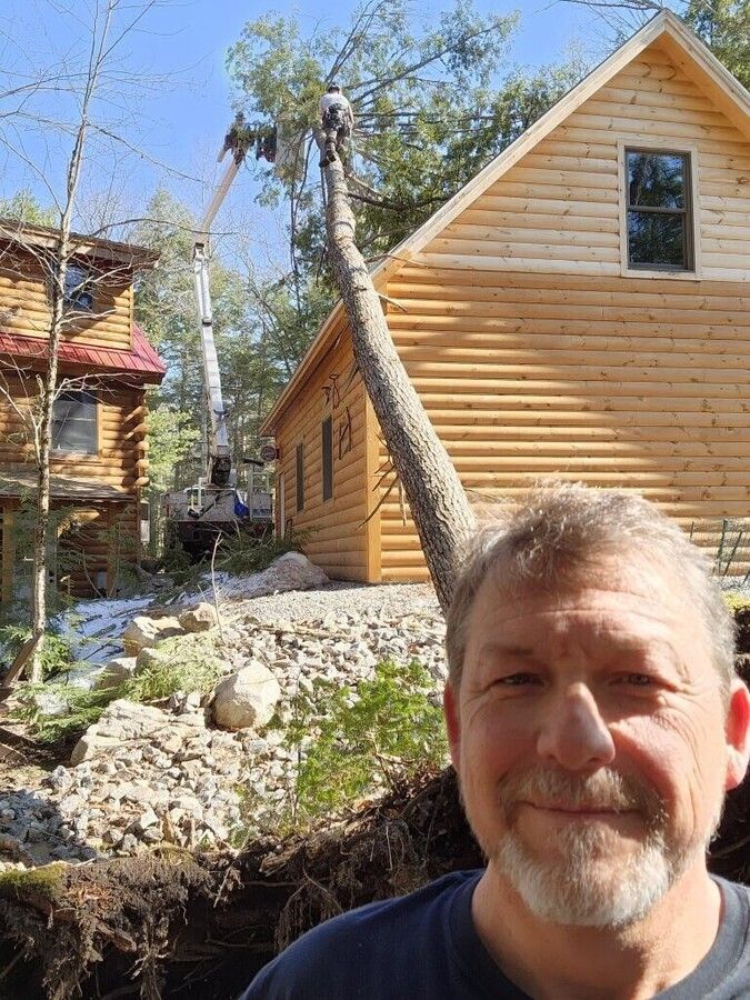 A man is posing for a picture in front of a log cabin.
