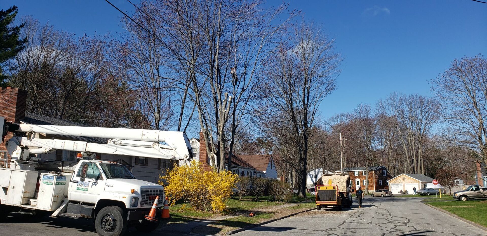 A white truck with a crane on top of it is parked on the side of the road.