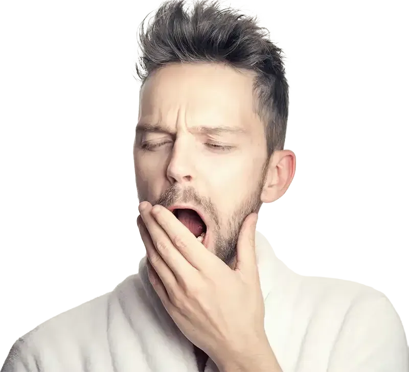 Woman in striped jumpsuit, hand in hair, sitting in tall grass, looking relaxed.