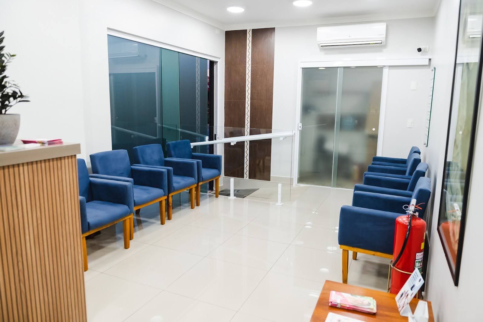 Uma sala de espera com cadeiras azuis e um extintor de incêndio.
