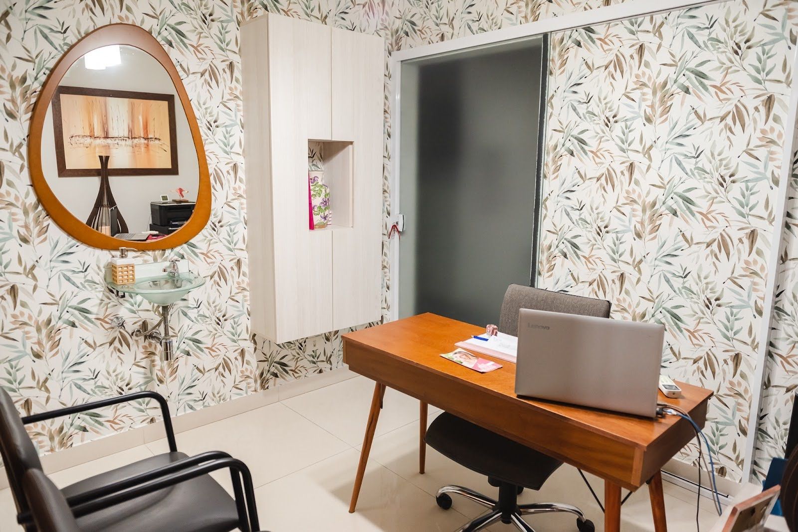 Um quarto com mesa, cadeira, laptop e espelho.